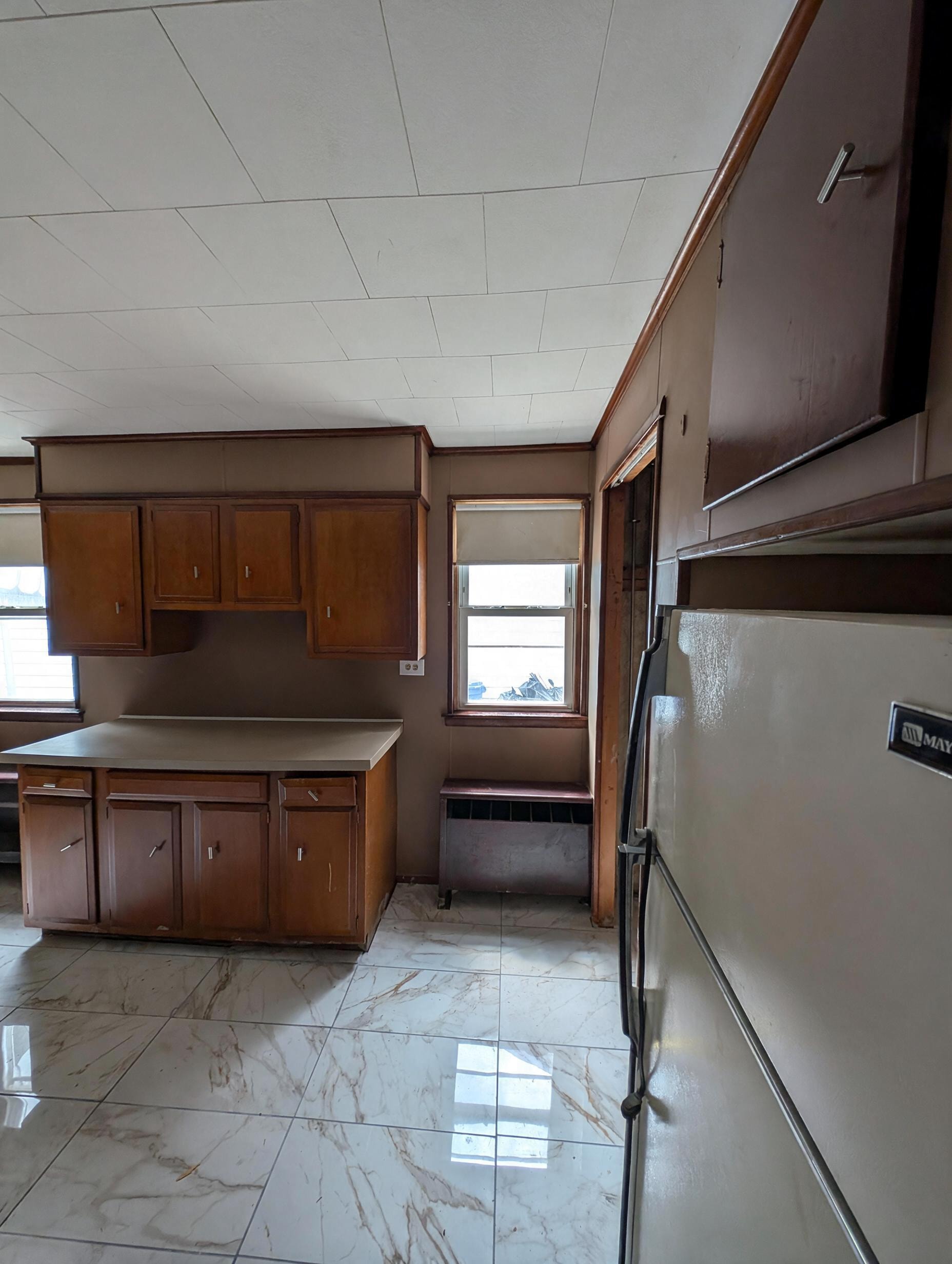 Kitchen with wood cabinets and marble tile floor, side angle