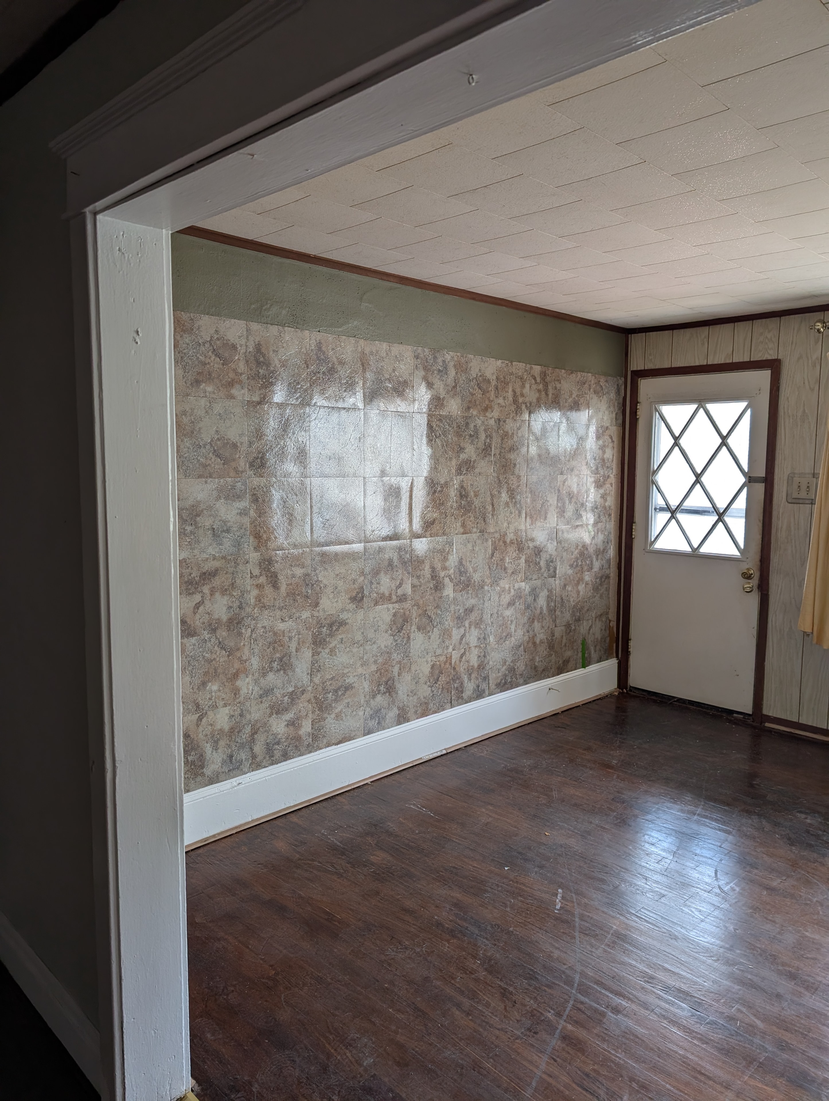Room with stone tile accent wall, diamond window door, and dark hardwood floors