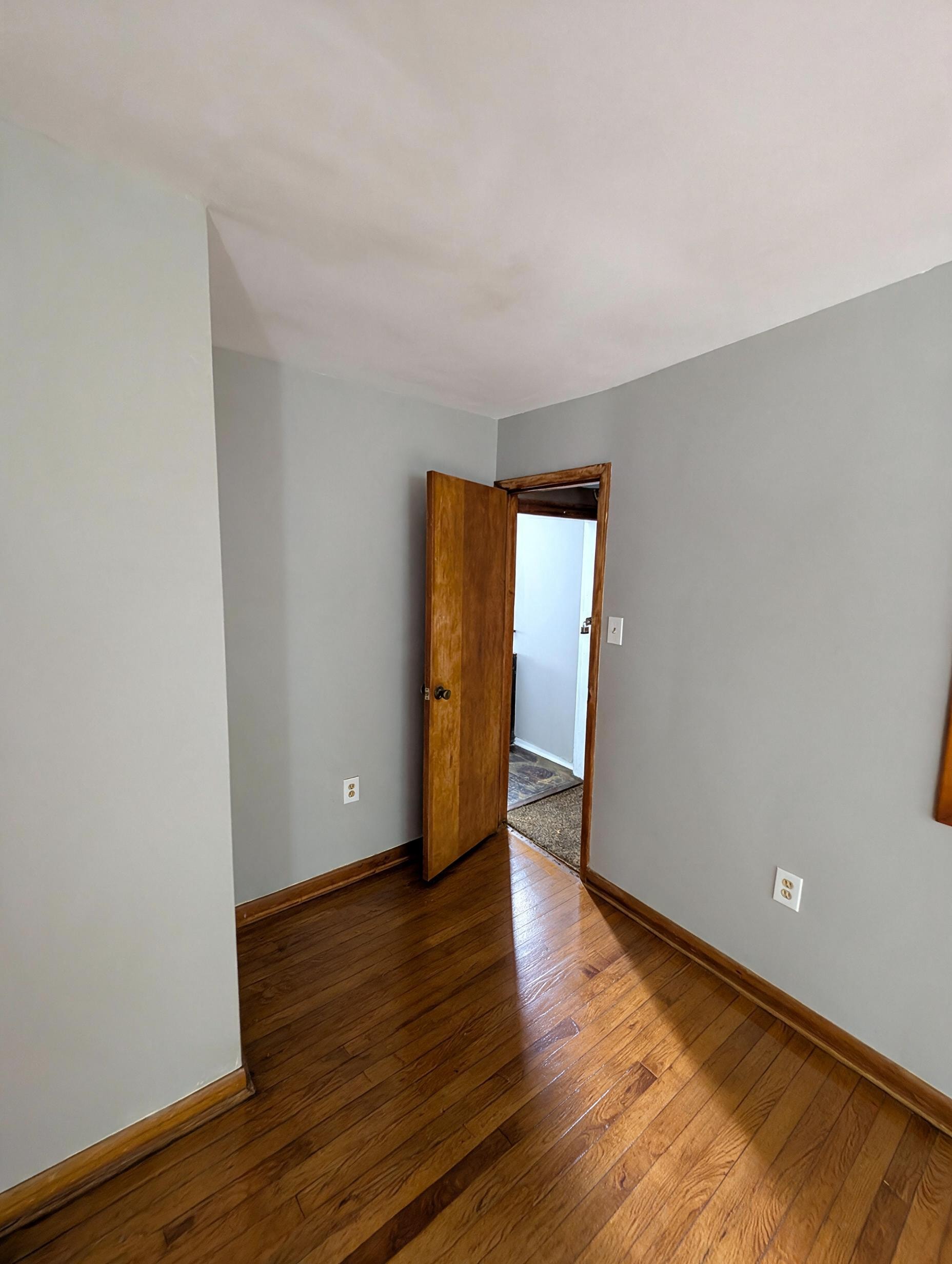 Bedroom with gray walls, open wood door, and hardwood floors