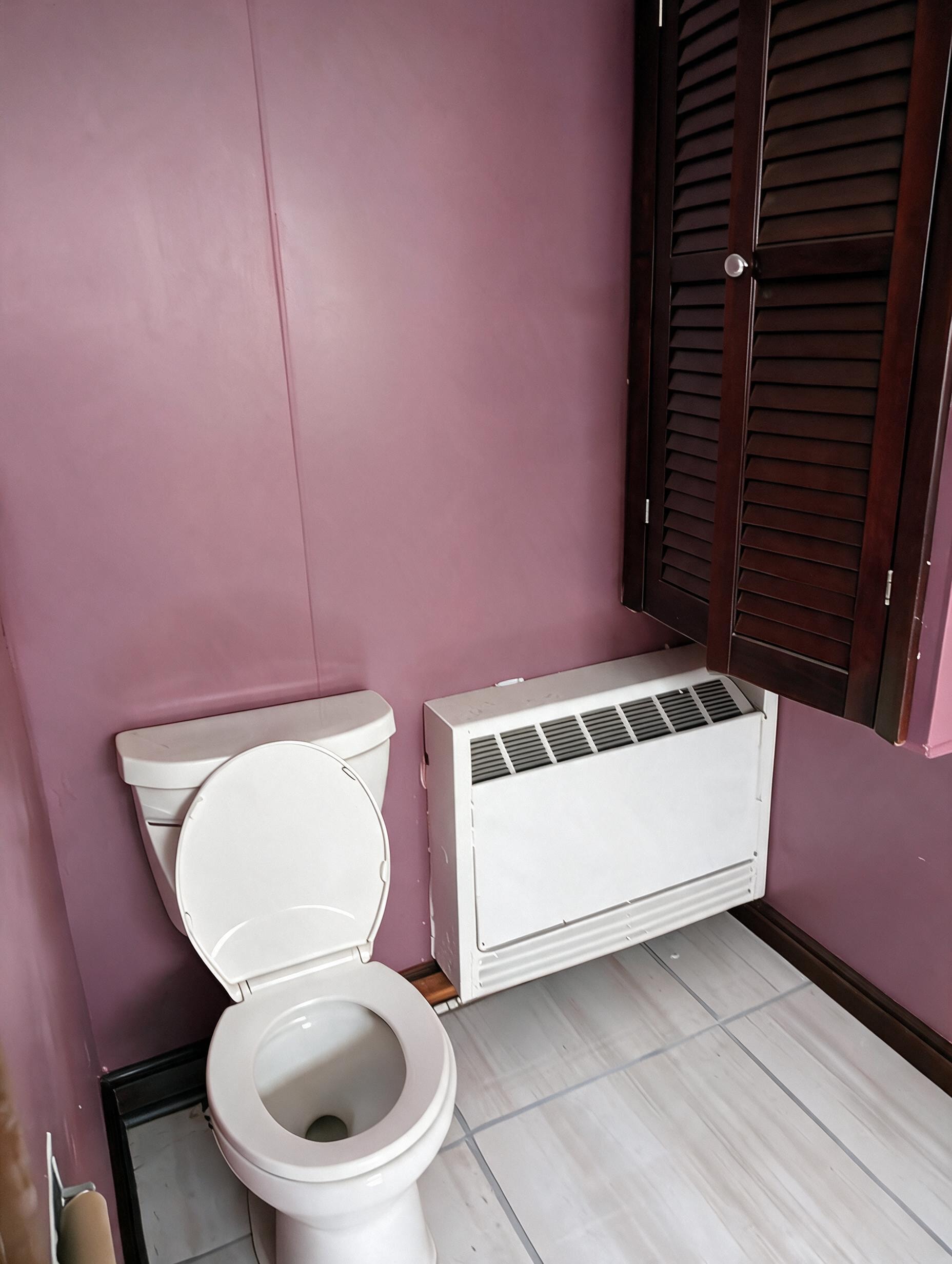 Bathroom with toilet and wall AC unit