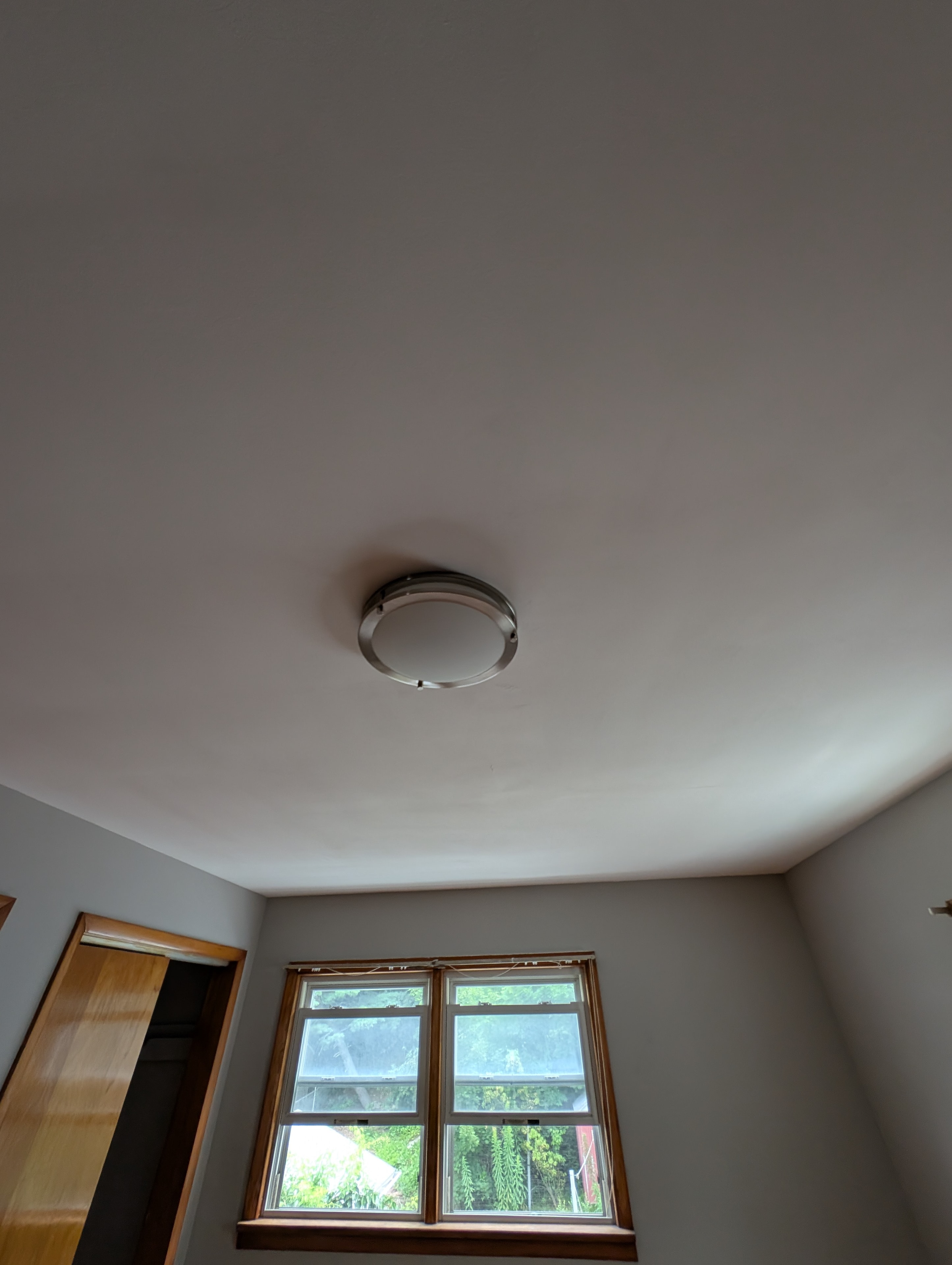 Bedroom ceiling with flush mount light and double windows